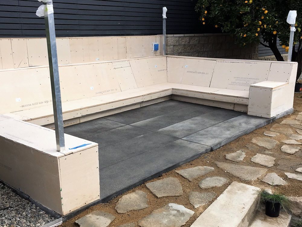 A patio with a couch and benches in the middle of it.
