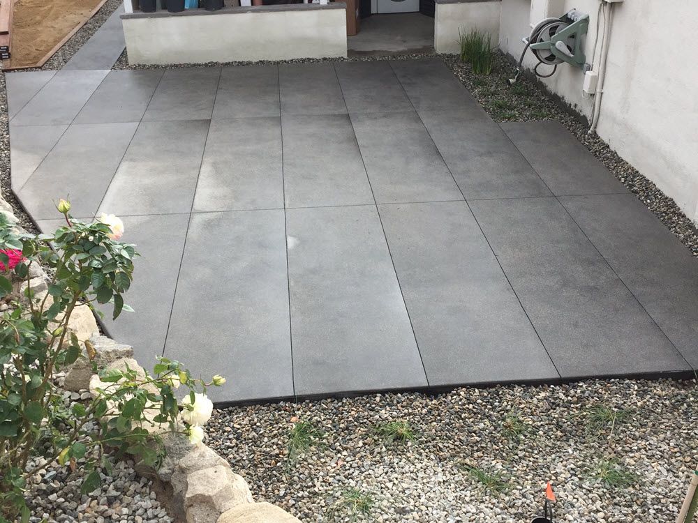 A patio with tiles and gravel in front of a house.