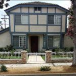A large house with a fence around it and a tree in front of it.
