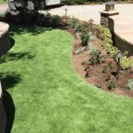 A lush green lawn with a patio in the background.