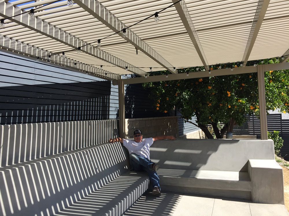A man is sitting on a bench under a pergola