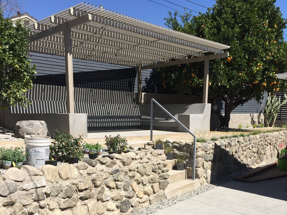 A stone wall with stairs leading up to a pergola