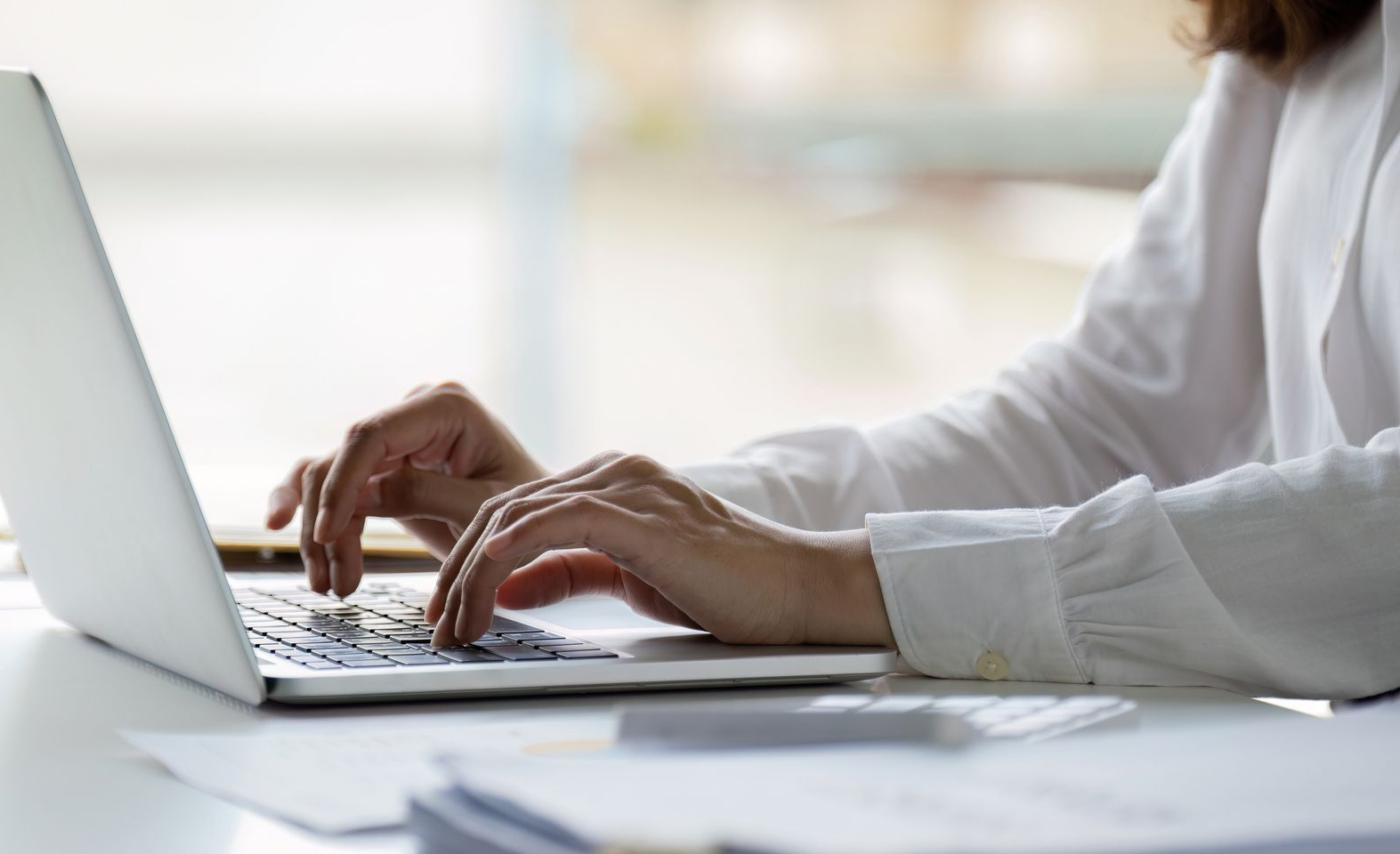 a person wearing white typing on a laptop