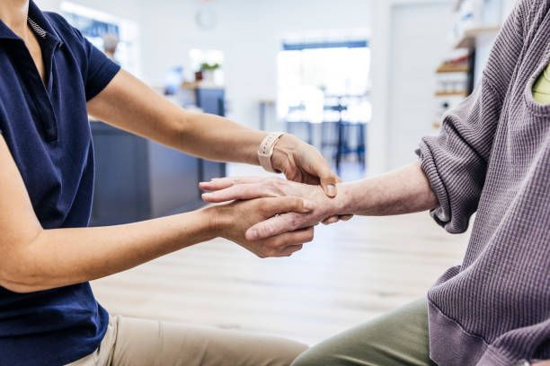 A woman is holding the hand of an elderly woman.