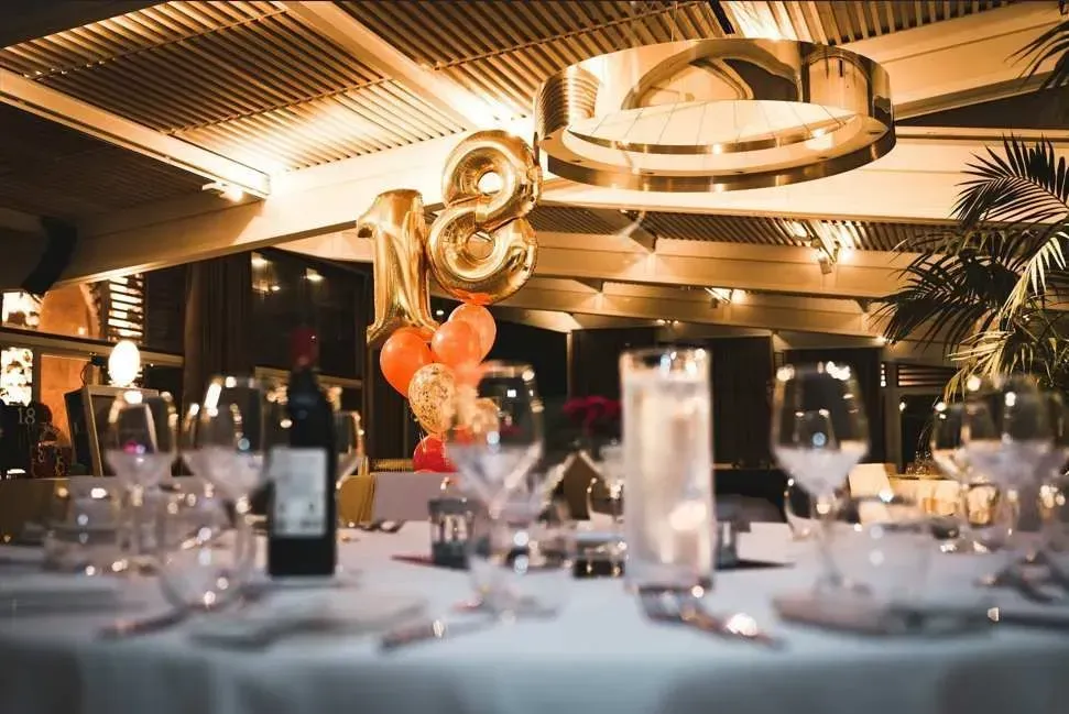 Elegant banquet table set with glassware and candles under warm chandelier lighting