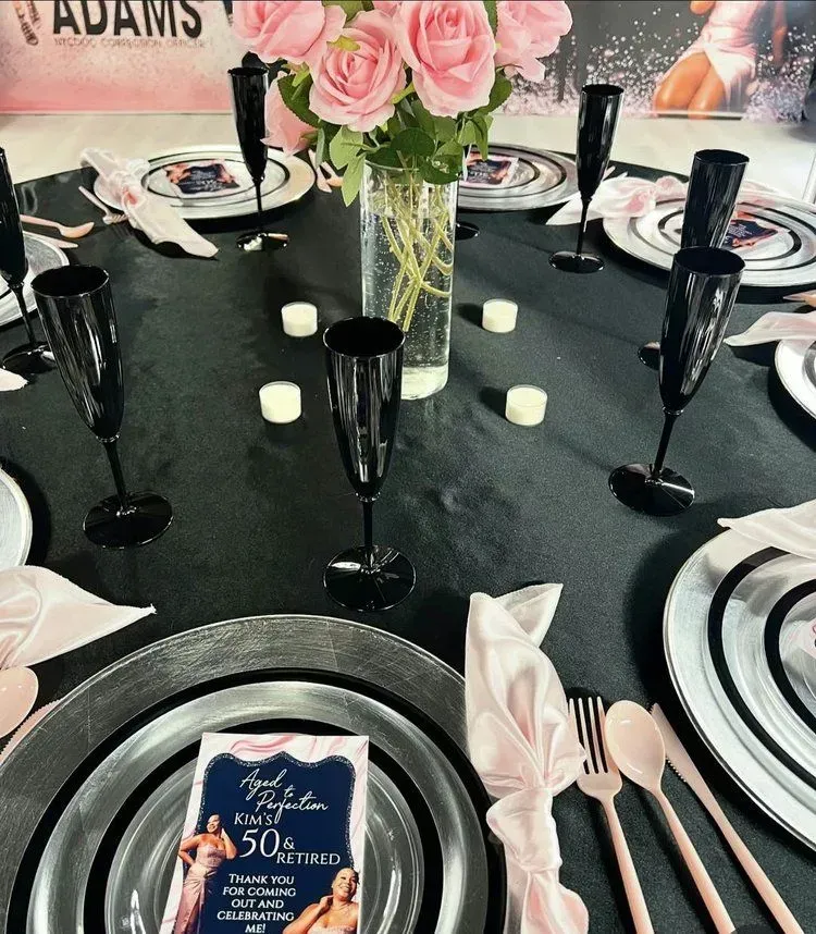 Elegant black table setting with pink roses, candles, and silver dinnerware at a formal event