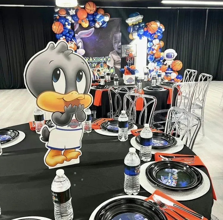 Looney Tunes birthday table with black plates, water bottles, and a cartoon character centerpiece