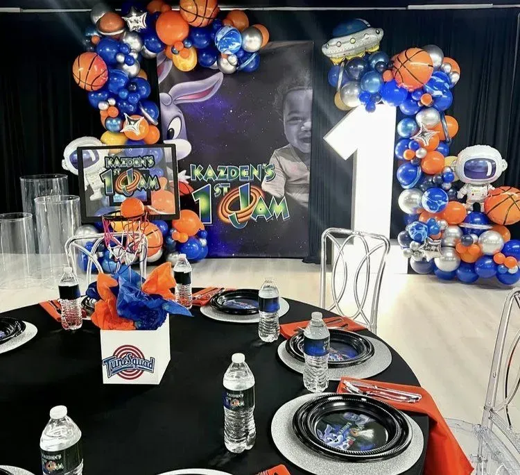 Basketball-themed party table with blue, orange, and black decorations, plates, balloons