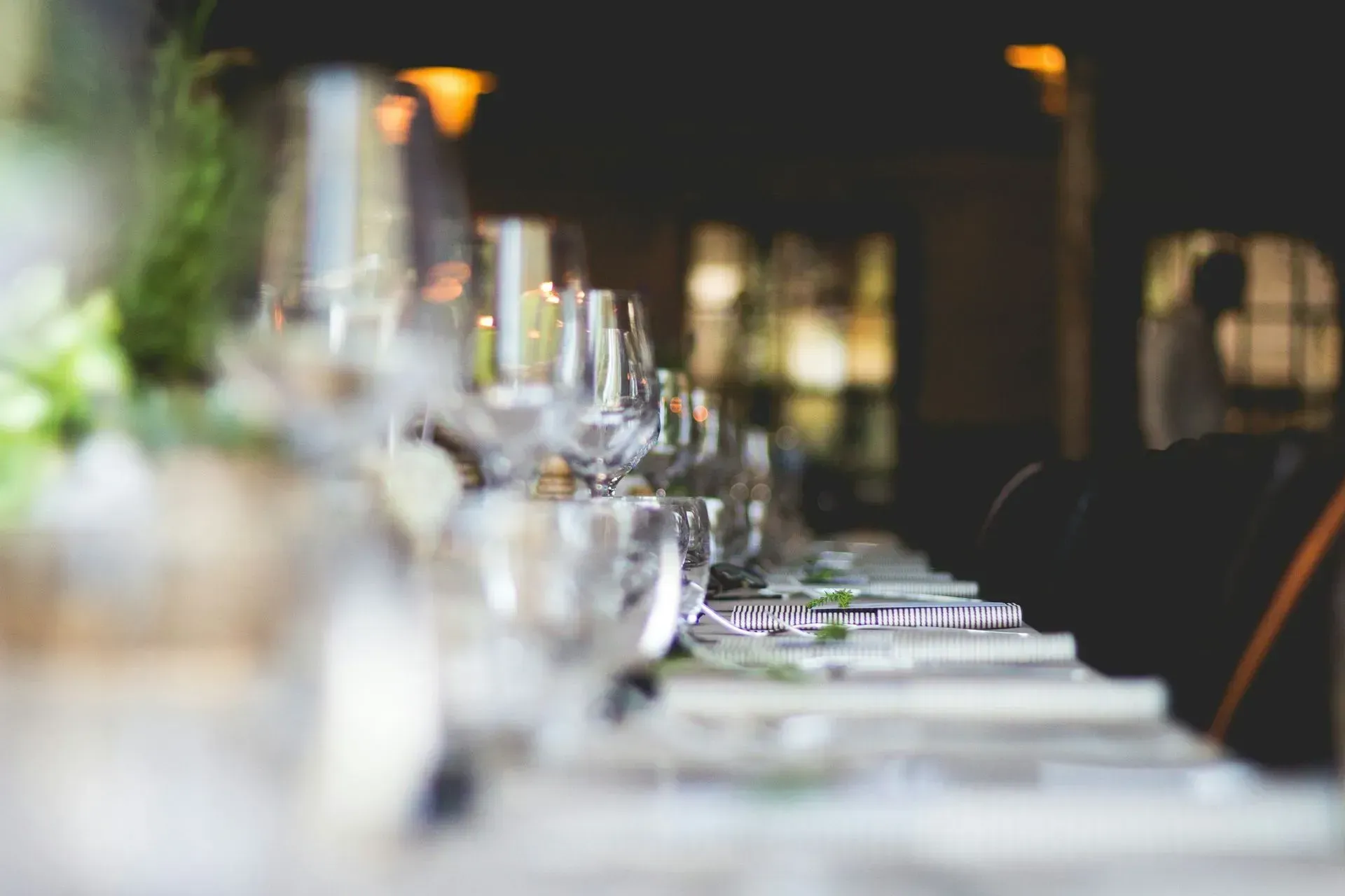 Elegant dining table set with wine glasses and plates in a softly lit restaurant