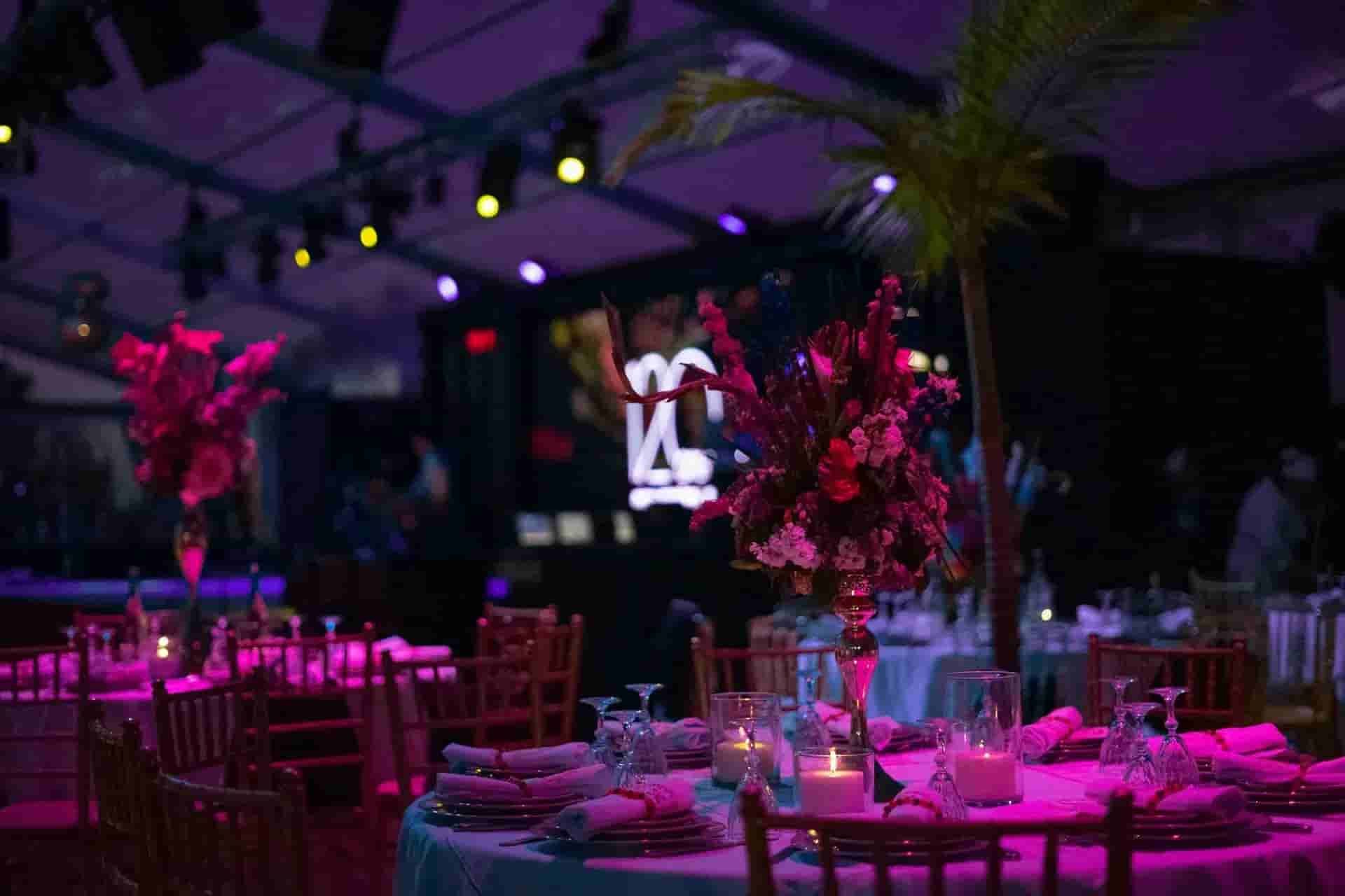 Elegant banquet hall with pink-purple lighting, round tables