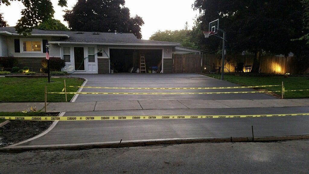 Driveway with yellow caution tape in front of a house with a basketball hoop.