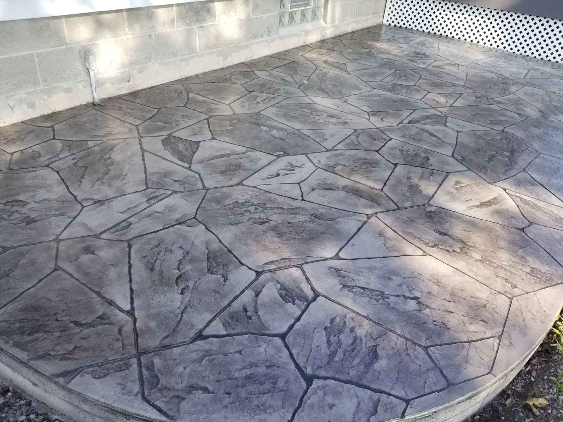 Gray, textured concrete patio with irregular stone pattern.