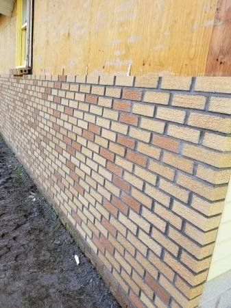 Brick wall with alternating light and dark brown bricks on a building's exterior.