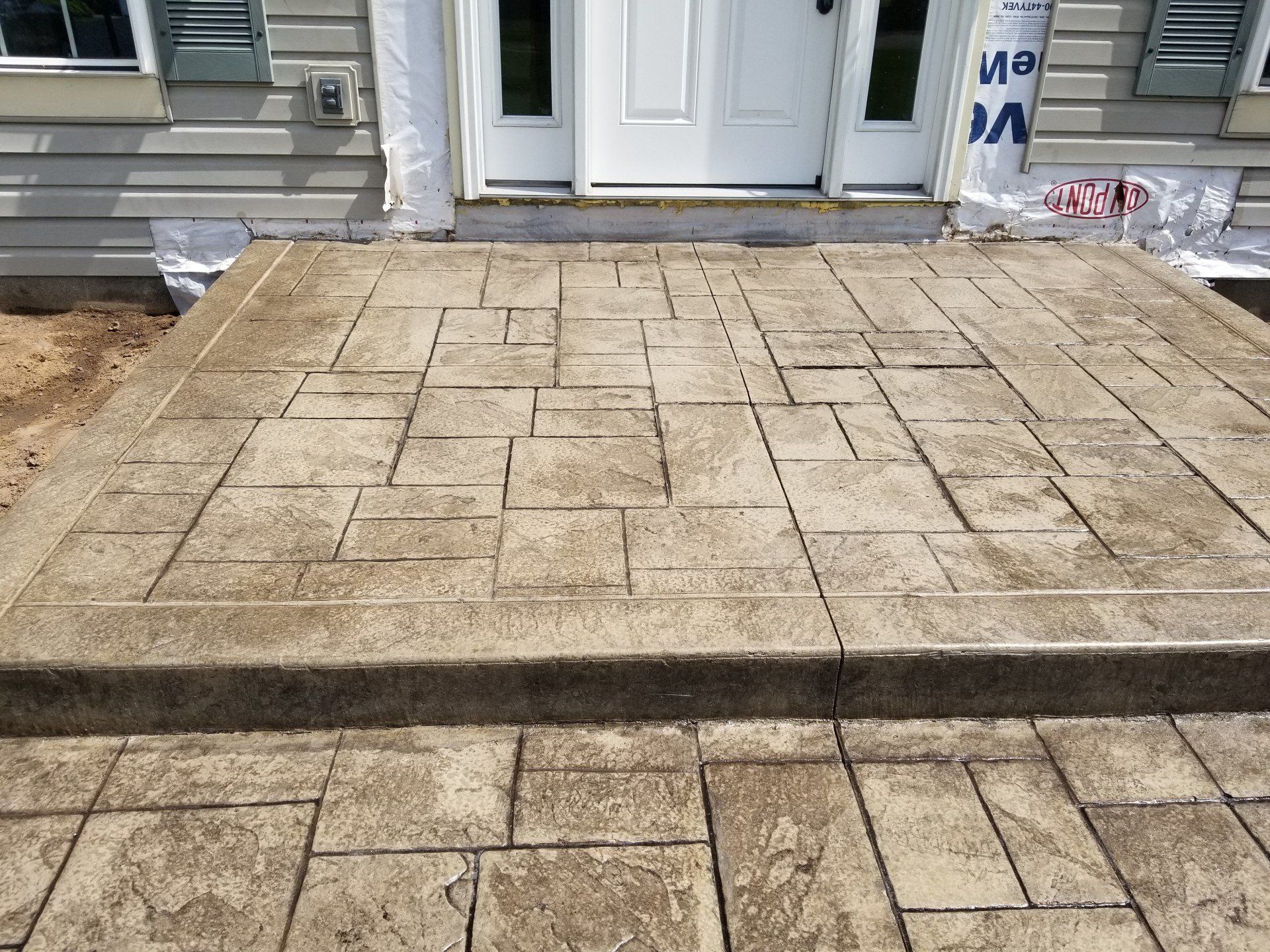 Concrete front porch with step, stamped with a geometric stone pattern.