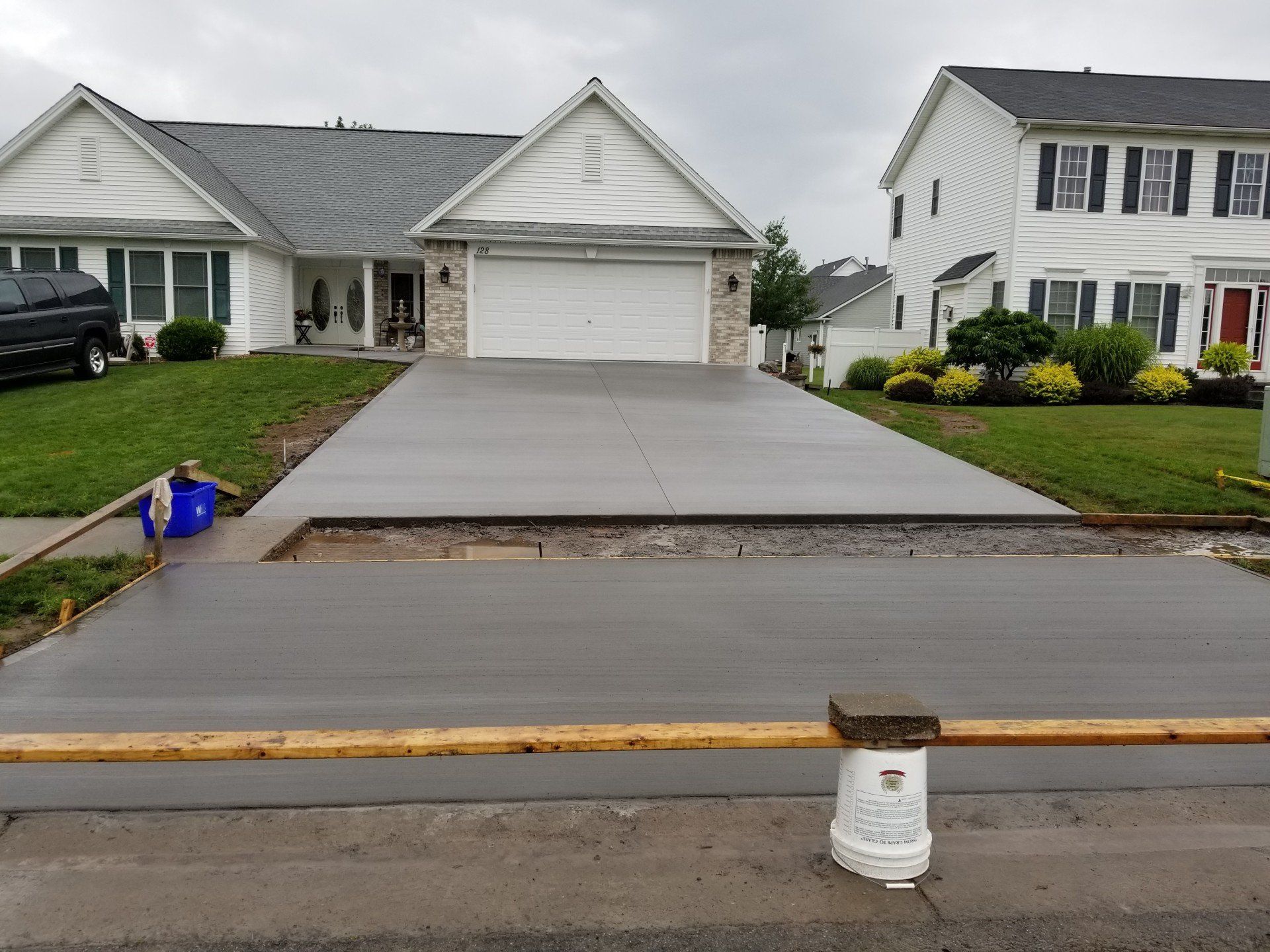 Newly poured concrete driveway in front of a house. Border of new concrete in foreground.