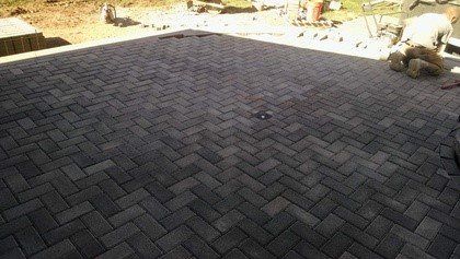 Herringbone-patterned brick patio under construction, dark gray bricks.