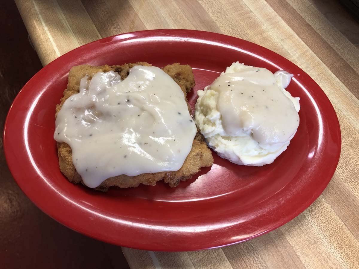 A red plate topped with fried chicken and mashed potatoes