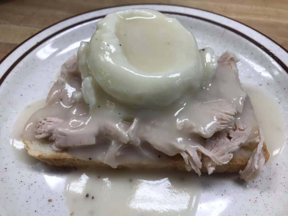 A close up of a plate of food with meat and a poached egg on top.