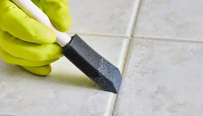 A person is cleaning a tile floor with a sponge.