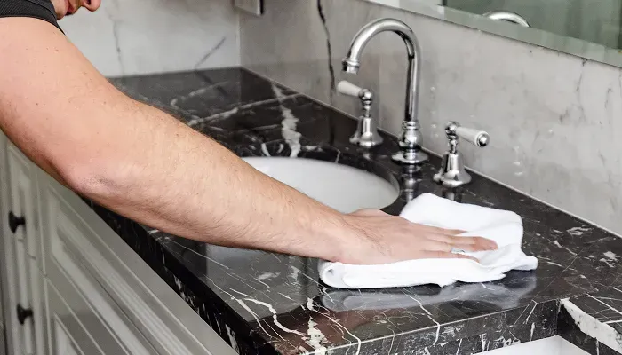 Wiping a black marble countertop with a cloth