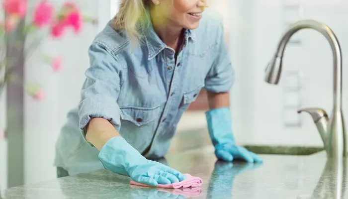 Woman cleaning a marble countertop with gloves
