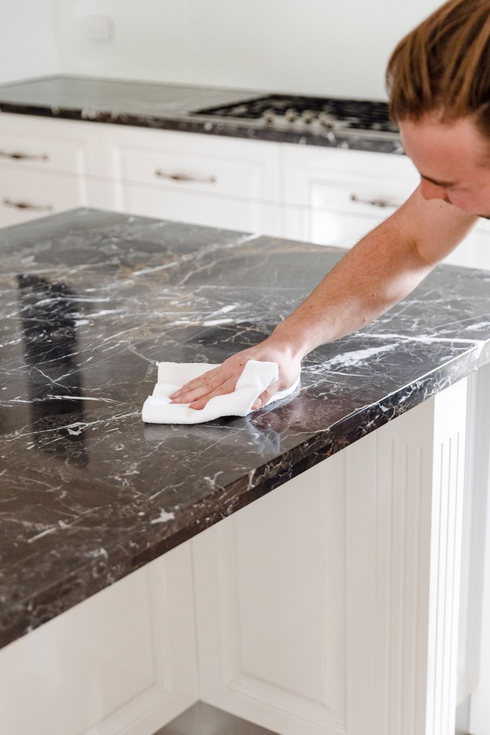 A person is cleaning a marble counter top with a cloth.
