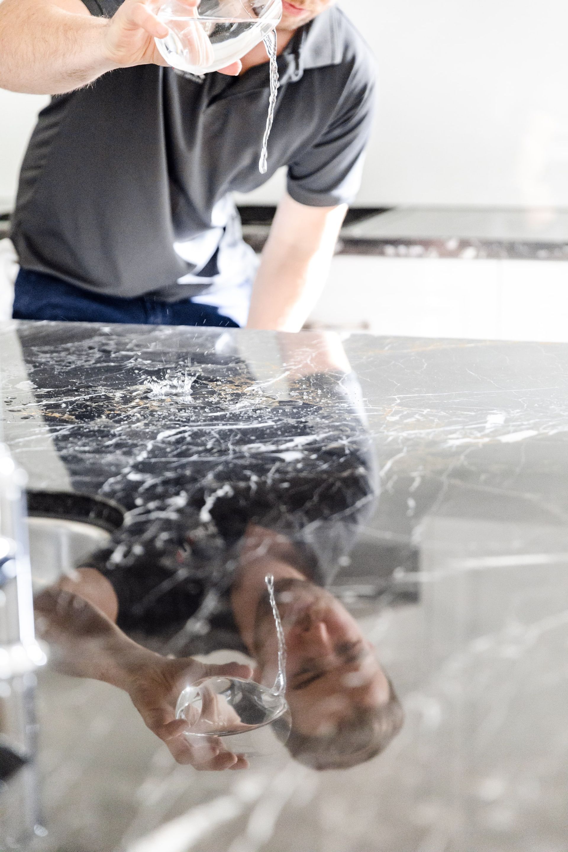 A man is pouring water into a glass on a counter.