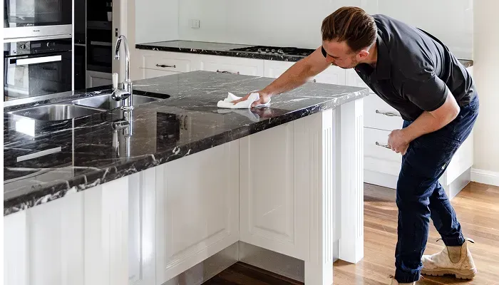 A man is cleaning a kitchen counter with a cloth.