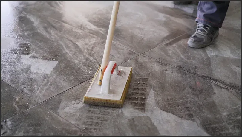 Professional cleaner using a specialized tile and grout cleaning tool on a heavily stained tiled floor in Canberra.