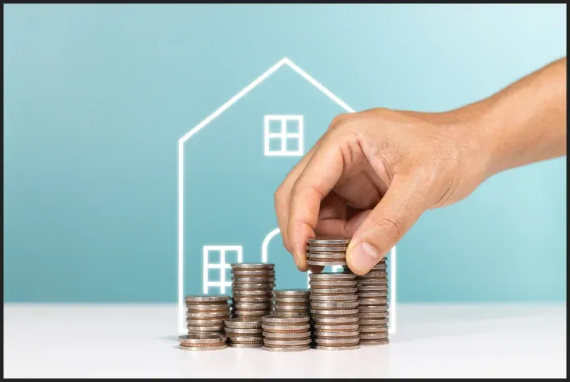 Hand stacking coins in front of a house outline, symbolising increased home value