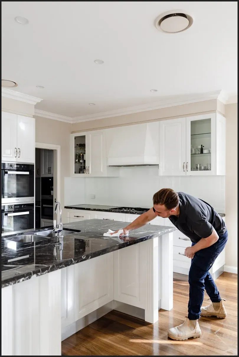A man is cleaning a kitchen counter with a cloth.