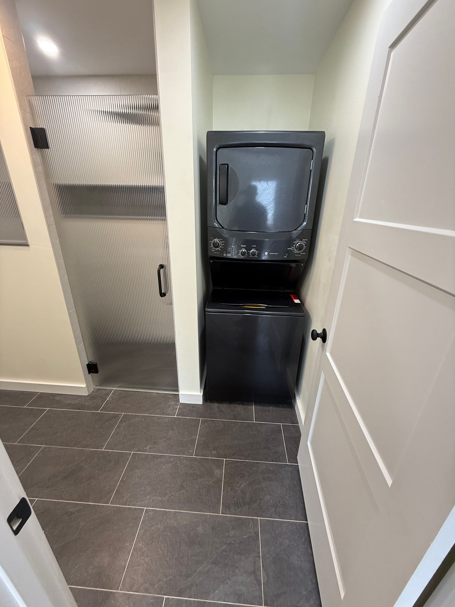 Hallway with black mini fridge and water dispenser beside open white doors on tiled floor