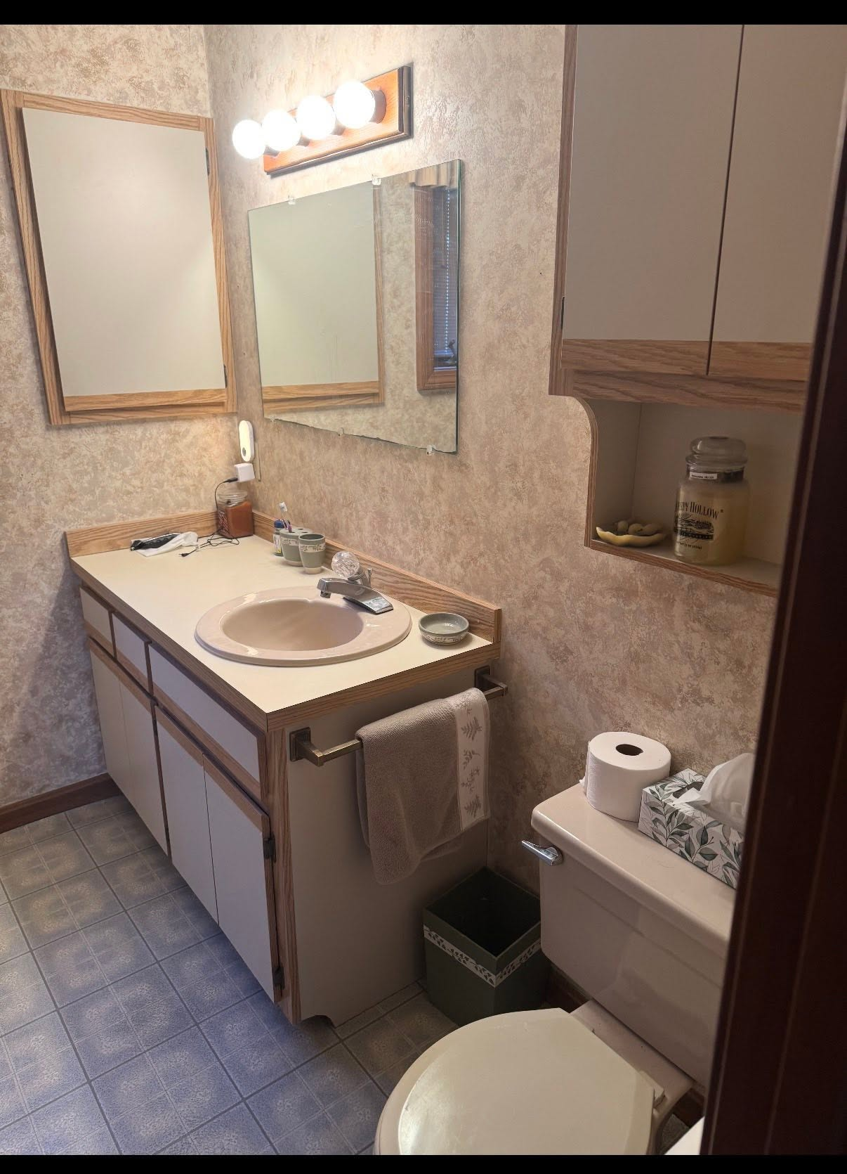 Small bathroom with sink, mirror, vanity, toilet, and beige walls.