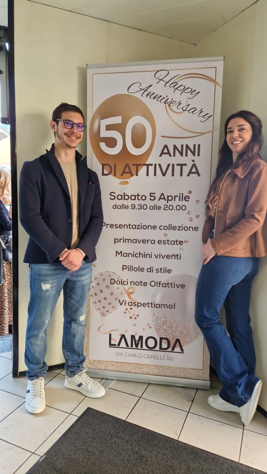 Due persone posano accanto a uno striscione che celebra