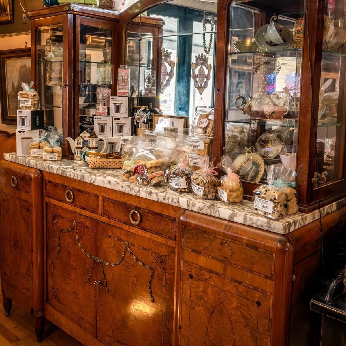 A wooden cabinet with a marble counter top is filled with lots of food.