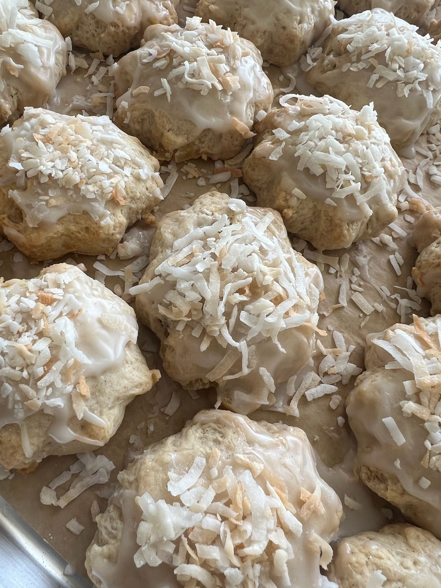 A close up of a tray of cookies with coconut on top.