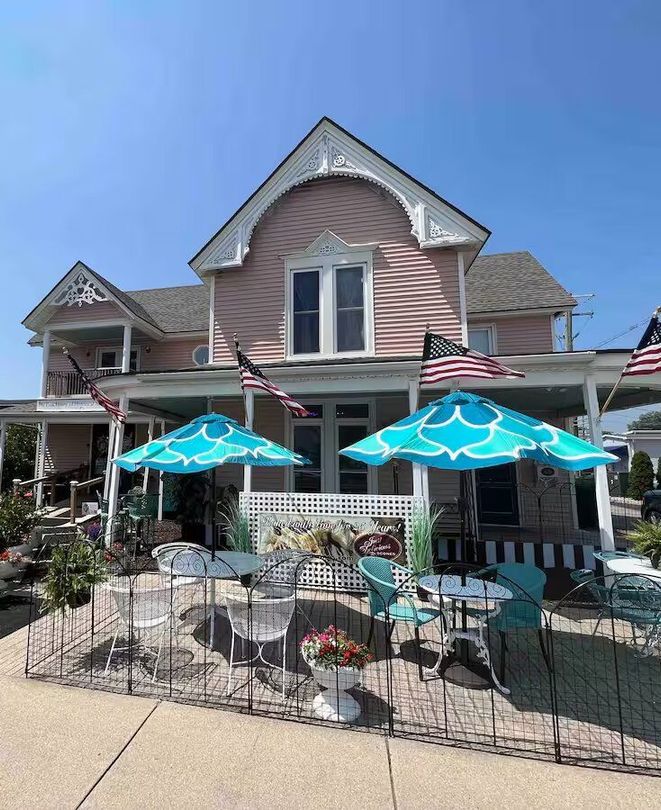 A large pink house with tables and umbrellas in front of it.