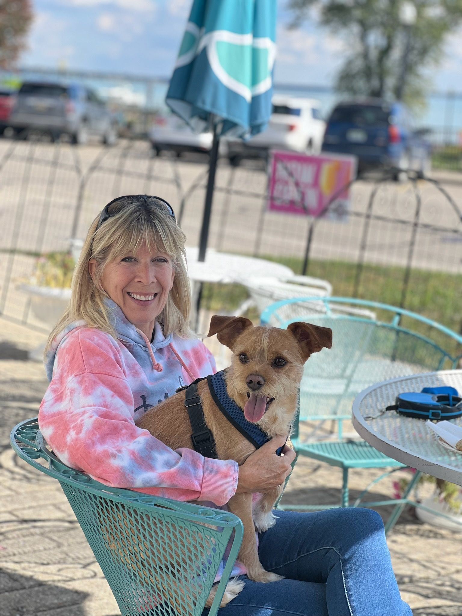 A woman is sitting in a chair holding a small dog.