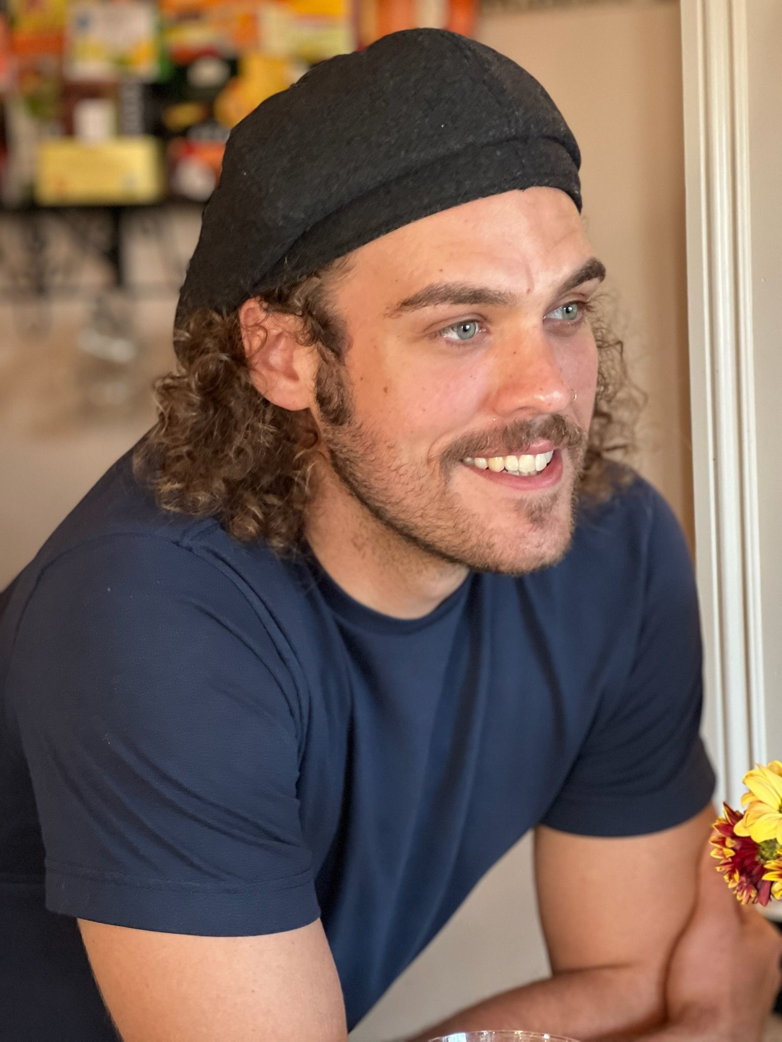 A man wearing a black hat and a blue shirt is smiling