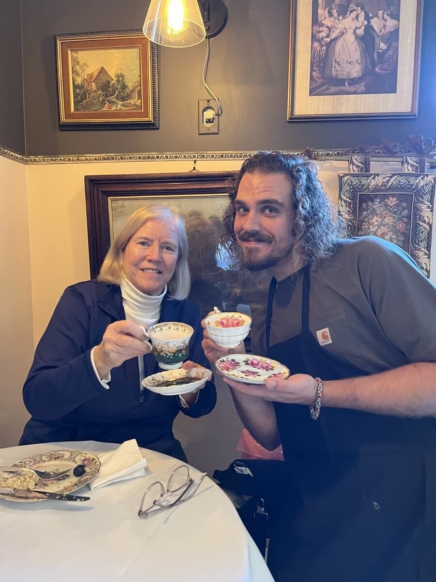 A man and a woman are sitting at a table holding cups of tea.