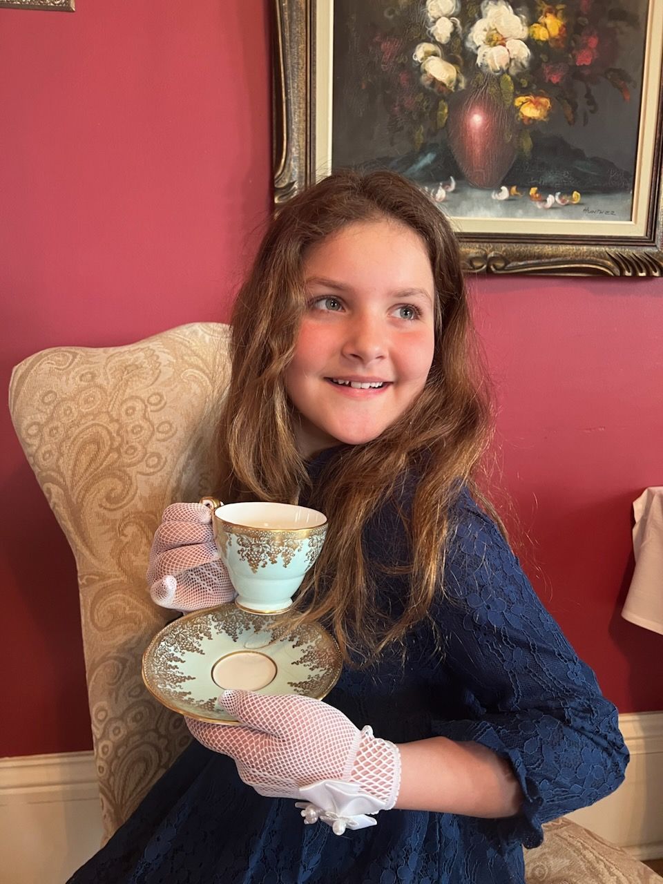 A young girl drinking tea in the Pink House Tea Room.
