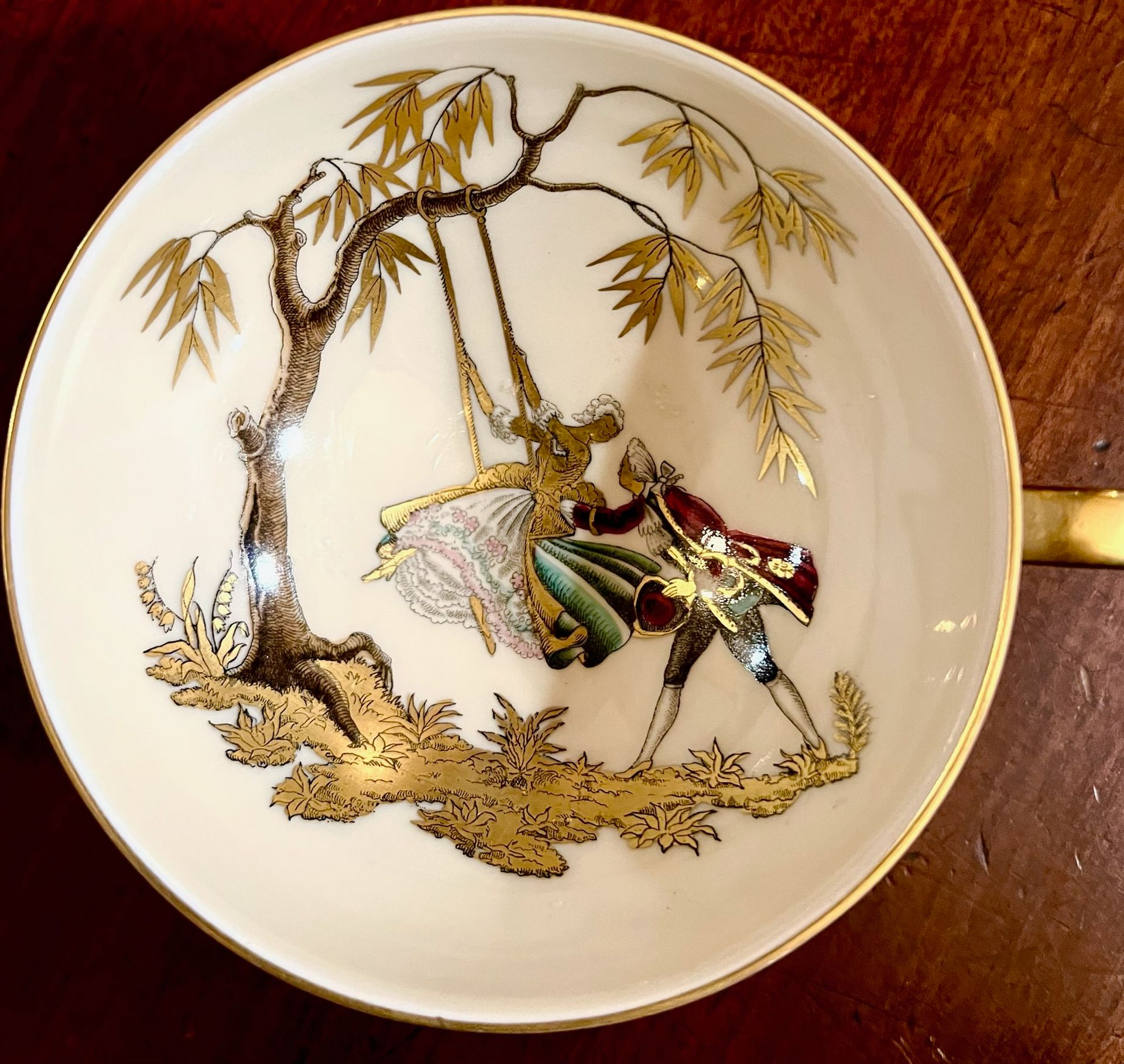 A white plate with a man and woman on a swing.