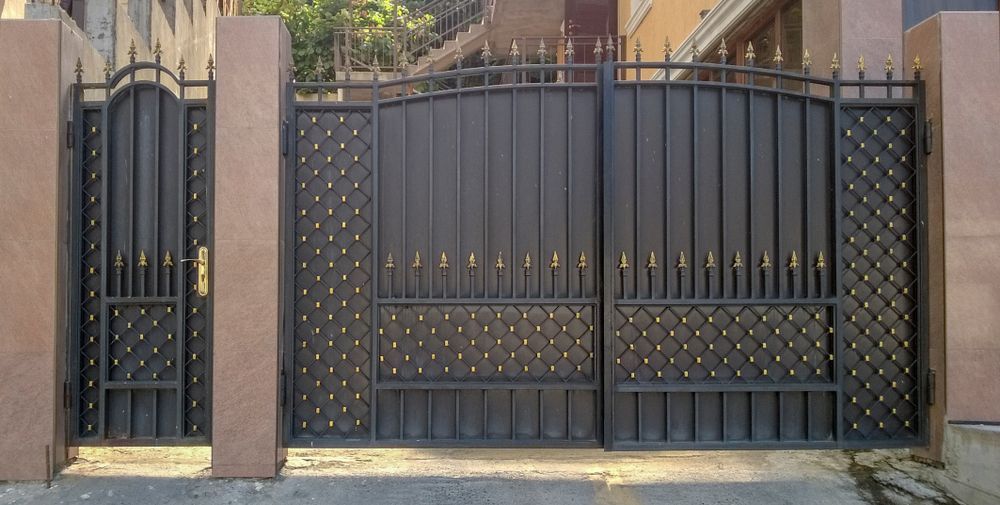 A Wrought Iron Gate is Surrounded by Stone Pillars in Front of a Building — Febos Welding and Engineering In Dapto, NSW