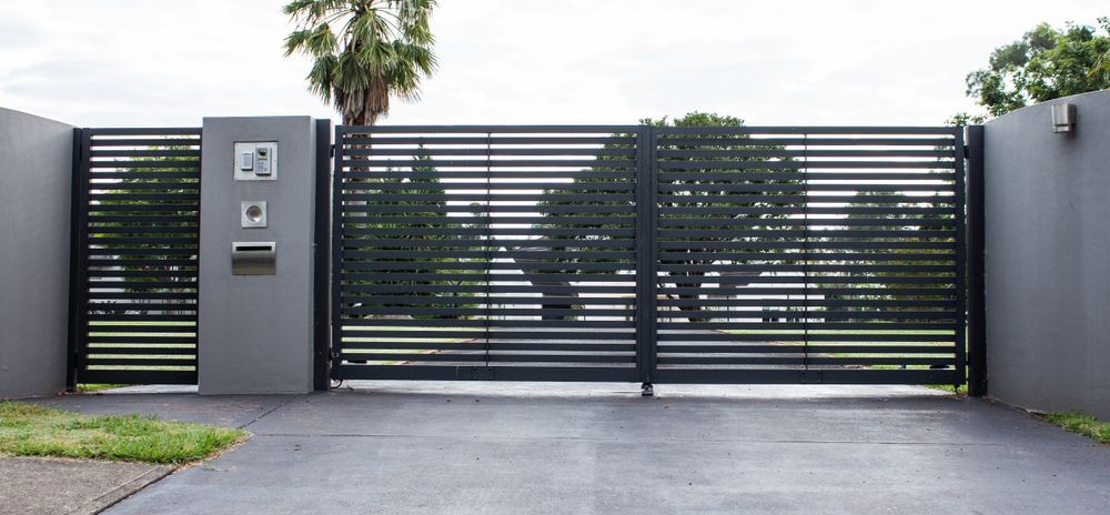 A Black Gate is Open to a Driveway With Trees in the Background — Febos Welding and Engineering In Thirroul, NSW