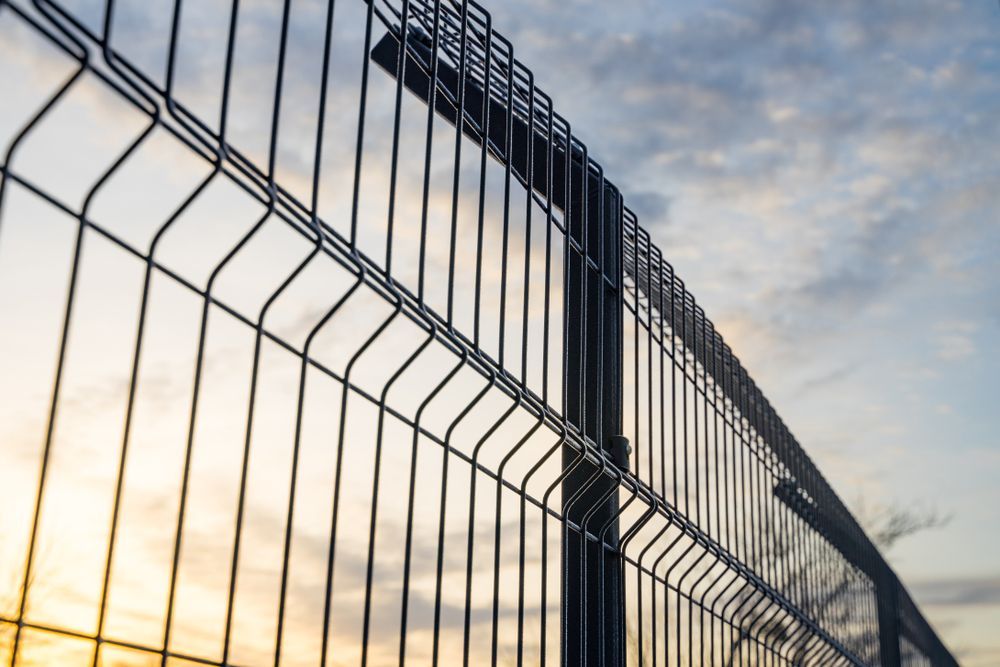 A Close Up of a Metal Fence With a Sunset in the Background — Febos Welding and Engineering In Shellharbour, NSW
