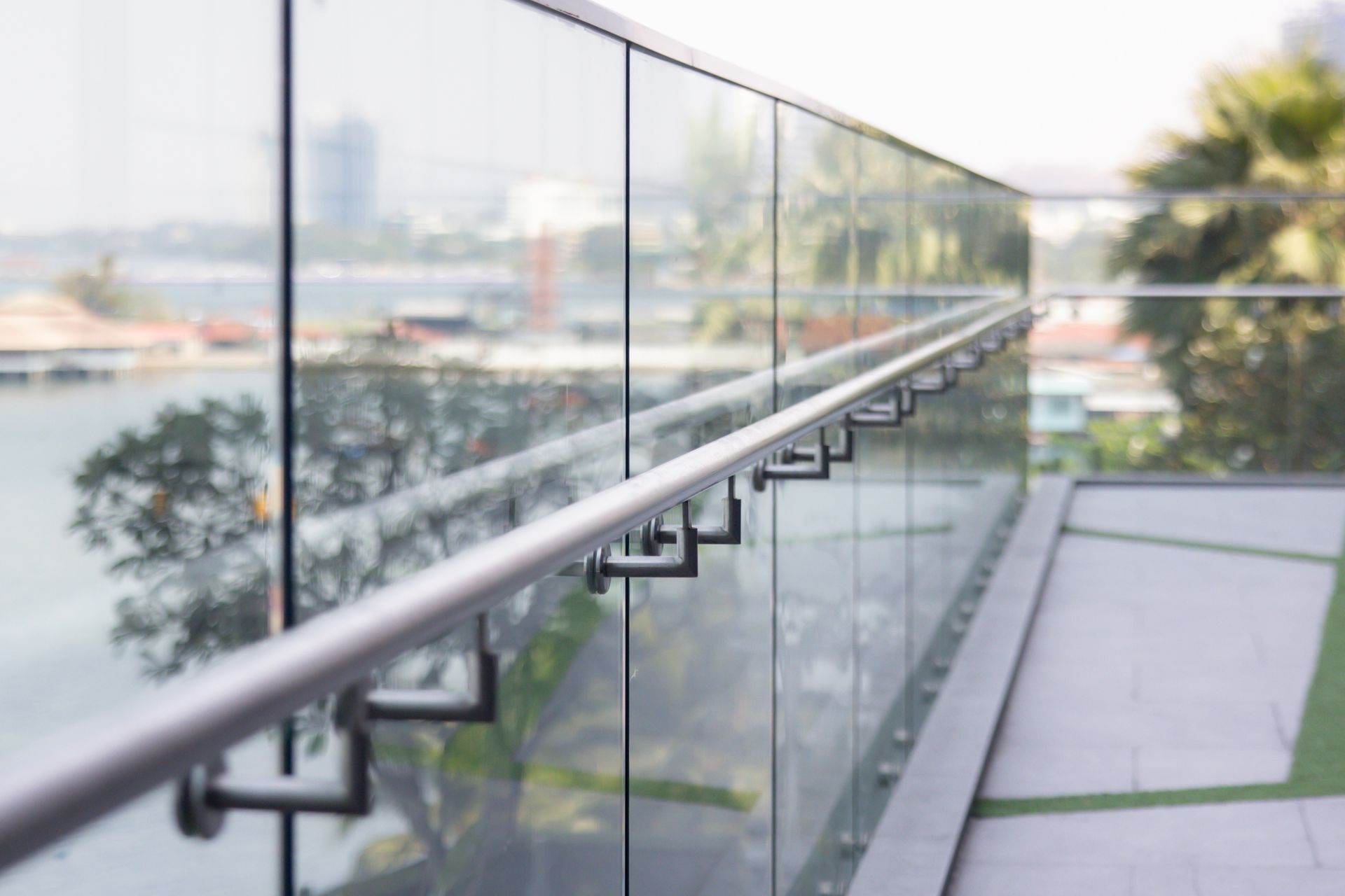 A balcony with a glass railing and a view of the city — Febos Welding and Engineering In Corrimal, NSW