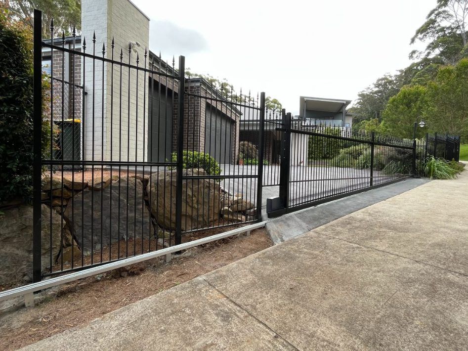 A Black Iron Fence Surrounds a Driveway in Front of a House  — Febos Welding and Engineering In Corrimal, NSW