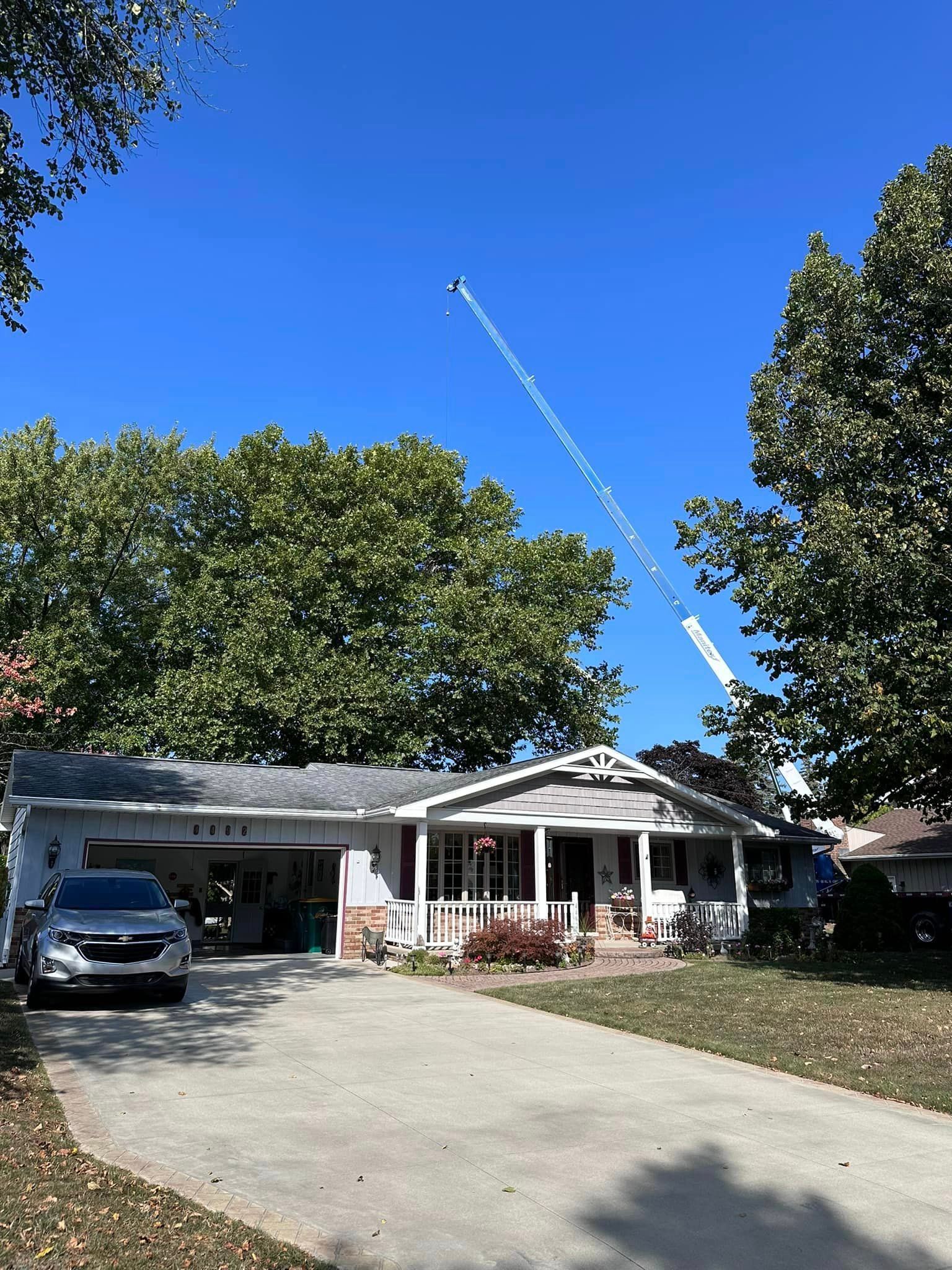 Legendary Tree Care LLC | white truck is parked in front of a house with a crane in the background.