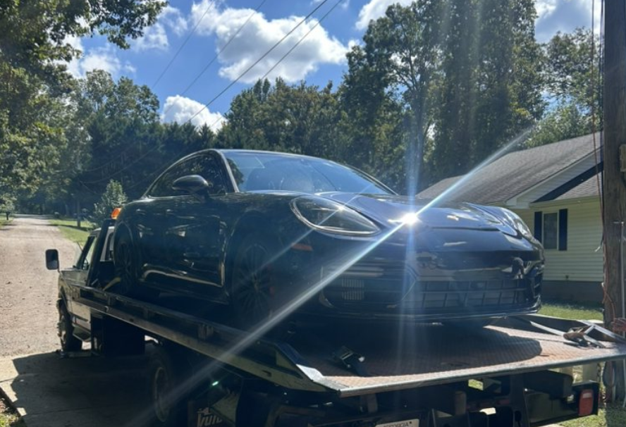 A black car on the back of a tow truck in Johns Creek GA