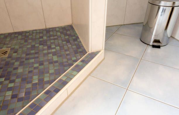 A bathroom with a tiled floor and a stainless steel trash can